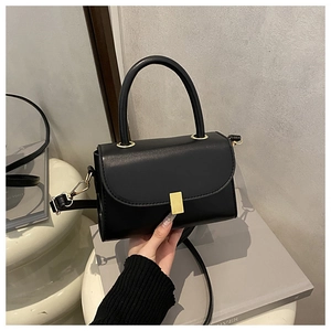 Détail d'un sac bandoulière en cuir noir minimaliste avec un fermoir doré métallique