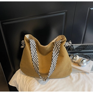 Detail of camel corduroy tote bag featuring a black and white twill woven shoulder strap