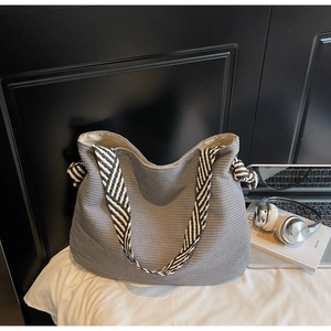 Detail of grey corduroy tote with black and white striped woven strap and knot decoration