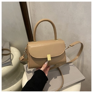 Détail du petit sac bandoulière beige minimaliste avec poignée ronde et fermoir doré