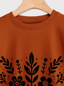 Detalle del cuello redondo acanalado y el estampado floral negro en una sudadera naranja