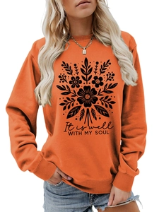 Detalle de sudadera naranja con gráficos florales y texto It is well with my soul impreso