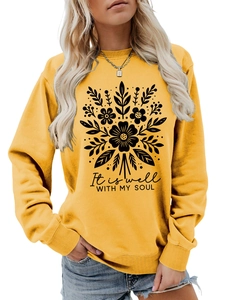 Detalle de sudadera amarillo jengibre con estampado botánico y cita en manuscrito