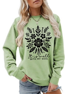 Detalle de sudadera verde claro con estampado floral y texto It is well with my soul