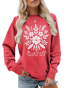 Detalle de sudadera roja de cuello redondo con estampado floral blanco y letras It Is Well
