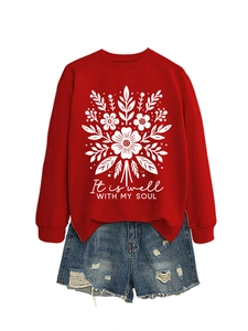 Detalle de sudadera roja con estampado floral y pantalones cortos vaqueros rotos