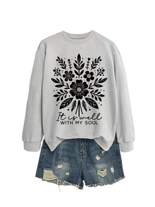 Detalle de sudadera gris con estampado floral y conjunto de pantalones cortos vaqueros