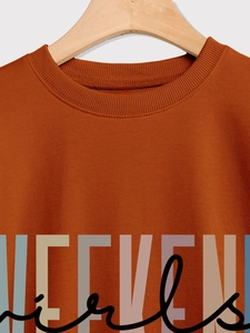 Close-up of brick red crewneck sweatshirt with WEEKEND girls printed text and knit texture