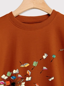 Detailed view of caramel crewneck sweatshirt featuring flying book illustration and ribbed collar