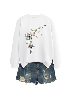 Close-up of white sweatshirt featuring creative dandelion and book print on fabric
