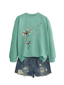 Flat lay of mint green long-sleeved sweatshirt with dandelion book print and denim shorts