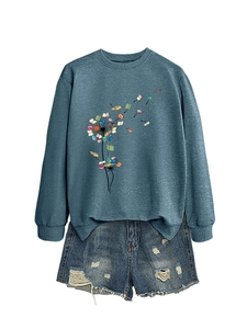 Flat lay of navy sweatshirt with dandelion book print and distressed denim shorts