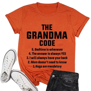 Flat lay of an orange cotton t-shirt with black The Grandma Code text and denim shorts