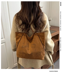 Sac cabas en daim marron avec illustration de dessin animé porté par un mannequin