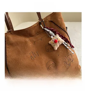Gros plan du cabas en daim marron avec graffiti et pendentif étoile en peluche