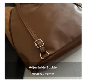 Détail de la boucle dorée réglable et texture de cuir mat sur le sac cabas marron