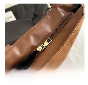 Vue détaillée de la fermeture éclair dorée sur un sac cabas en cuir marron de qualité