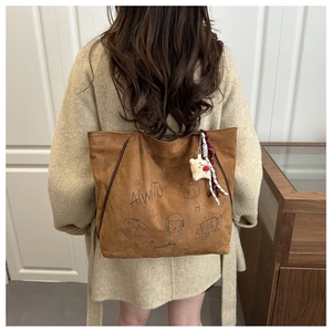 Detail of brown suede tote bag with cartoon illustrations and plush star charm pendant