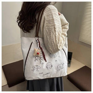 Detail view of canvas tote bag with cartoon illustration and brown leather shoulder strap