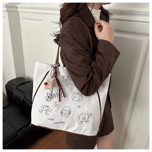 Canvas-Tote-Bag-Detail mit Comic-Illustrationen, Plüschbär-Anhänger und Schleife