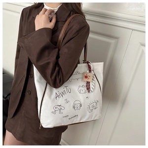 Detail der weißen Canvas-Tasche mit Comic-Illustrationen und Brot-Plüschanhänger