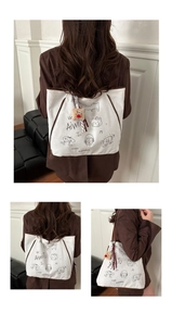 Détail du sac fourre-tout en toile blanche avec graffitis noirs et bordure marron