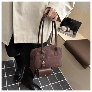 Gros plan d'un grand sac cabas en daim marron foncé avec mini pochette et longues anses