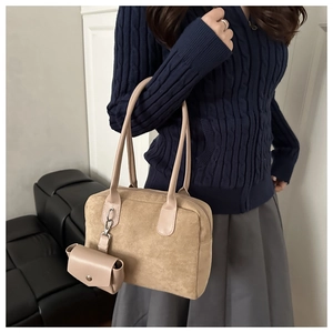 Detail of beige suede handbag with detachable mini pouch and long shoulder straps
