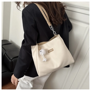 Detail of off-white PU tote bag with brown FASHION label and white plush doll pendant