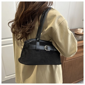 Close-up of black suede tote bag with metal buckle detail and dual handle structure