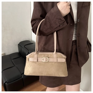 Detail of beige suede shoulder bag featuring slim straps and gold metal buckle accents