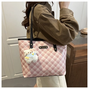 Detail of pink plaid tote bag featuring a cute teddy bear charm and metal logo plaque