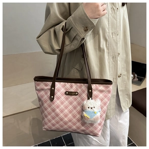 Close-up of pink checkered tote bag with brown leather handles and plush bear charm