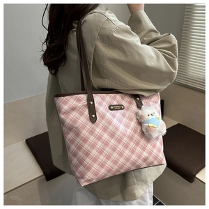 Side view of pink checkered tote bag with leather straps and a fuzzy bear charm