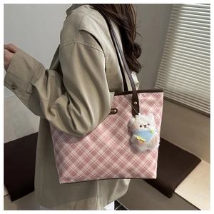 Detail of pink plaid tote bag with brown leather strap and white teddy bear charm
