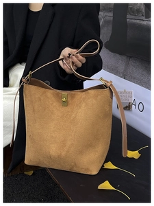 Detail of vintage brown suede tote bag with gold metal clasp and adjustable shoulder strap