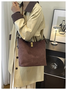 Detail of a brown suede hobo bag with gold metal twist lock and large capacity