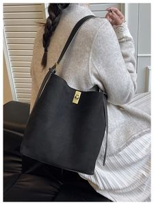 Macro detail of golden metal twist lock on black suede shoulder bucket bag