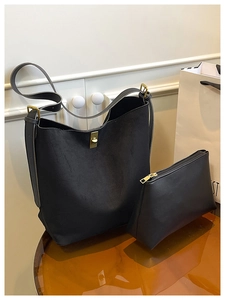 Detail view of black minimalist suede tote bag with matching pouch and gold twist lock