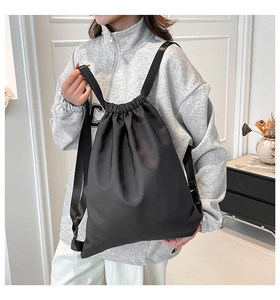 Close-up of black drawstring bucket backpack with adjustable wide straps and nylon texture