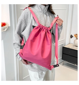 Detail of pink drawstring bucket bag with adjustable straps on a model back