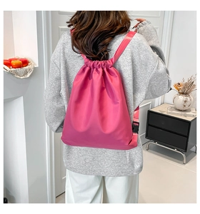Detail view of pink nylon drawstring backpack with adjustable straps on a female model