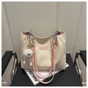 Détail d'un grand sac cabas bicolore avec sangles roses et breloque en peluche