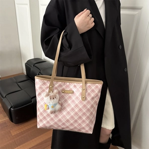 Pink plaid tote bag with khaki leather trim and a white plush bear charm on a model
