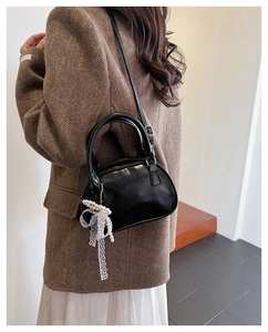 Chic black crossbody bag with white lace bow pearl charm worn on blazer outfit