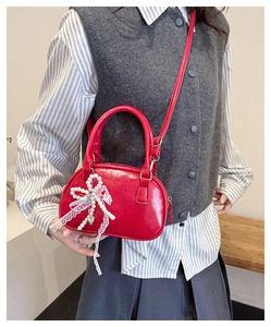 Detail of red patent leather mini bag featuring lace bow and pearl heart charm