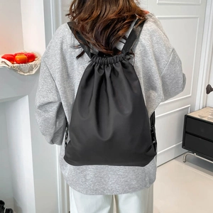 Minimalist black drawstring backpack for travel and gym shown on model back