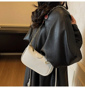 Detail of white pebble leather hobo bag featuring a cute red strawberry charm and chain