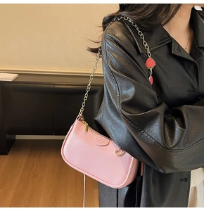 Detailed view of pink pebble leather bag with strawberry charm and gold chain strap