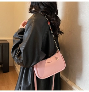 Detail of pink pebbled leather crescent bag with chic gold chain strap and branding